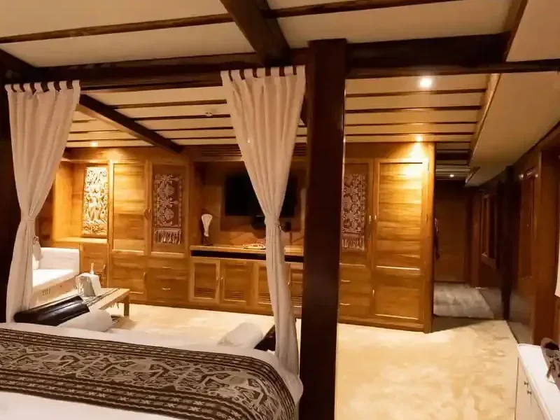 Master cabin aboard a group phinisi, teak joinery and four-poster bed